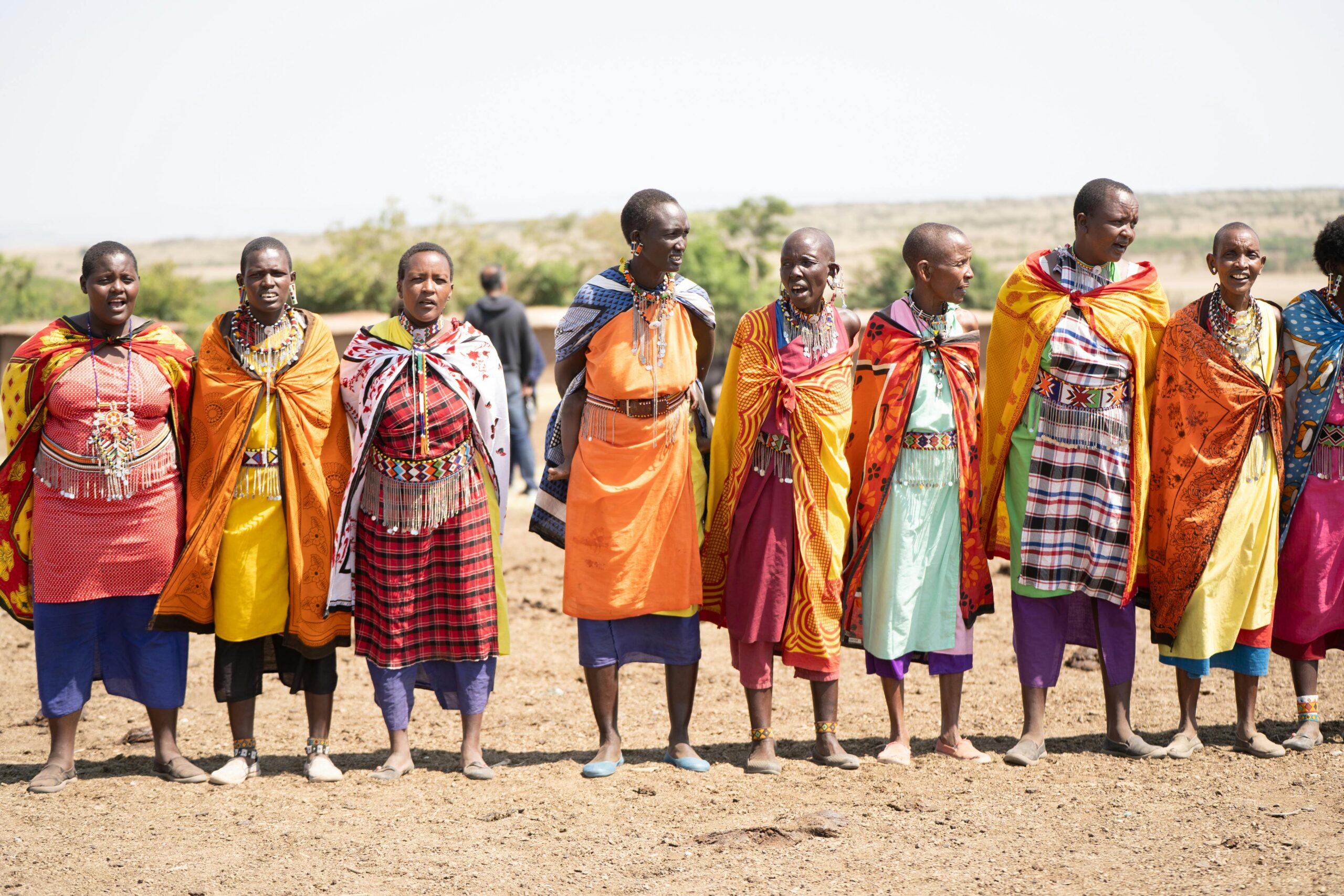A group of Maasai people in traditional attire celebrating in the Kenyan plains.